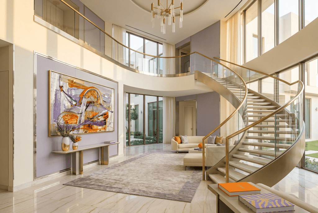 Gilded Traverse abstract artwork with a sweeping metallic gold and orange arc over lavender, violet and pale textured fields in a luxury two story foyer