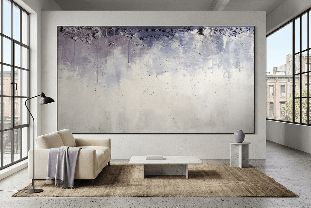 Overburden abstract artwork with a dark slate-violet plaster-like accumulation and fine drips above a chalk-white field with pale blue-grey veils in an industrial loft