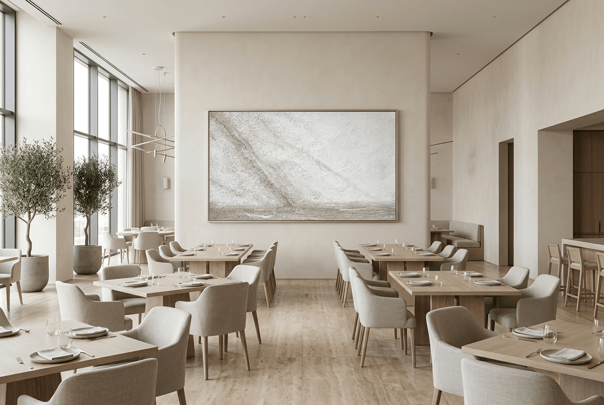 Unfilled Field abstract artwork with a pale cream and chalk-white textured field, a soft warm-grey diagonal drift, fine fissures, and a low stone-grey residue band in a modern restaurant